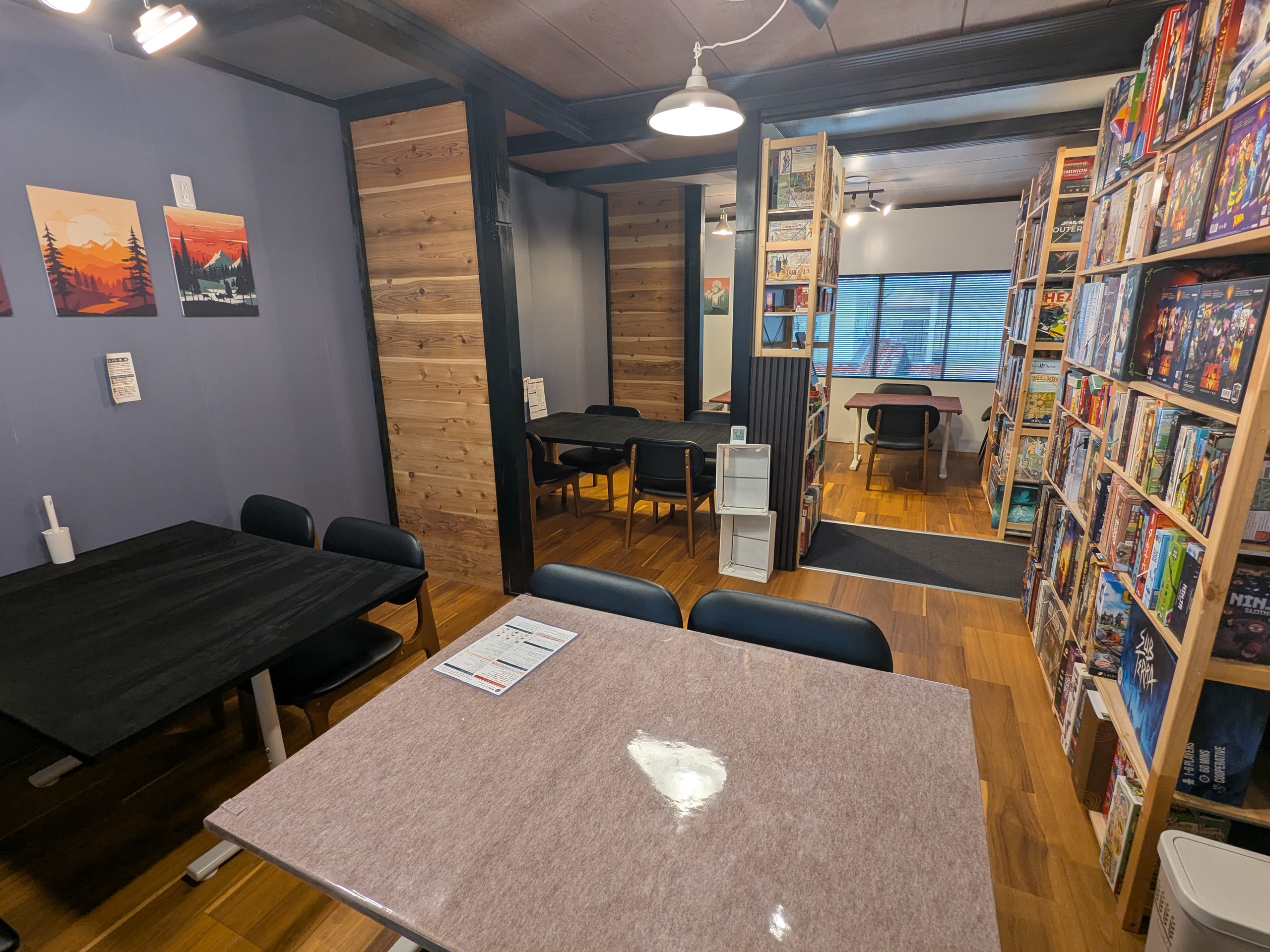 Inside Koma Board Game Café — a long counter, stools, and shelves of board games